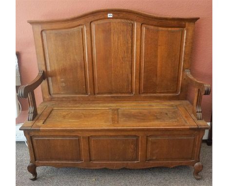 A French Oak Hall Bench/ Settle, with a panelled back rest above a hinged seat, raised on short cabriole legs, 112cm high, 12