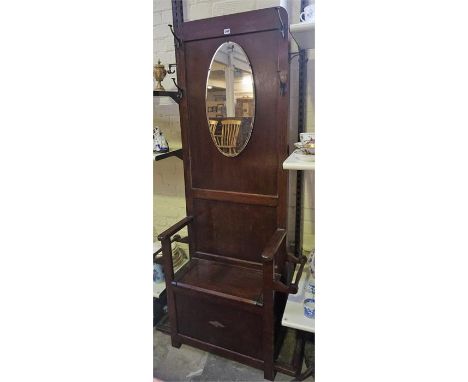An Oak Hallstand, with a mirror above a hinged seat, flanked with a stick stand compartment with drip tray below,185cm high, 