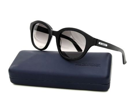 Damensonnenbrille, "Jil Sander". Schwarzes, strukturiertes Kunststoffgestell. Dunkel getönte Gläser mit Farbverlauf. L. Gebra