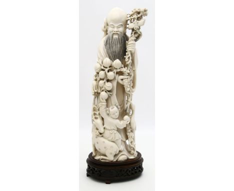 Große Skulptur eines Luohan mit Kind und Tieren. Elfenbein, 2.791 g. Vollplastisch geschnitzt. China, um 1900. H. 35,8 cm. Be