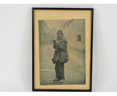 An early 20th century photograph, of an itinerant playing a violin, 28.5 x 20.5cm, framed