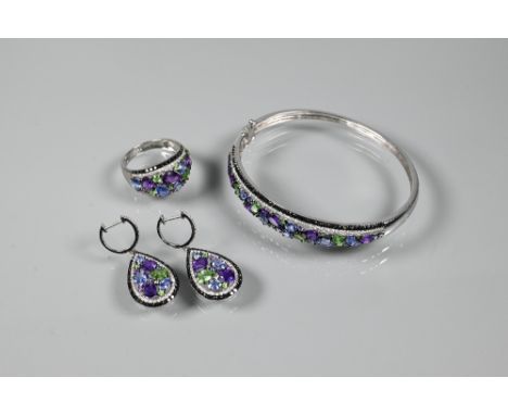 A suite comprising half-hinged bangle, bombe-style ring and pendant drop earrings, each set with mixed gemstones, white metal