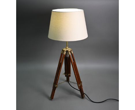 A mid-20th century wooden and brass telescopic tripod converted to a table lamp, with an off-white conical shade and black fl