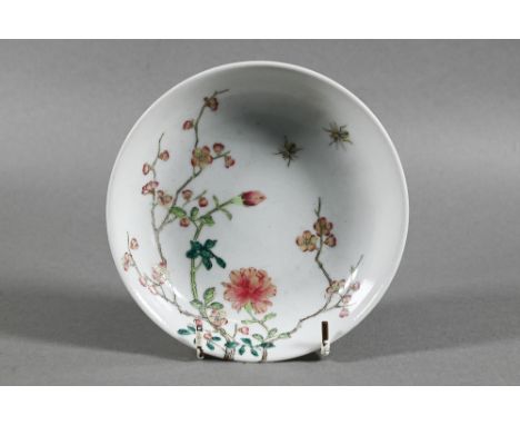 A Chinese famille rose dish painted in polychrome enamels with two insects, blossoming peony and prunus extending over the ri