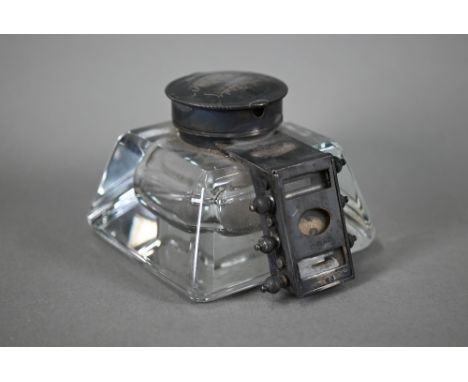 An unusual Edwardian glass inkwell, mounted with a hinged silver cover and perpetual calendar (lacks scrolls for day and mont