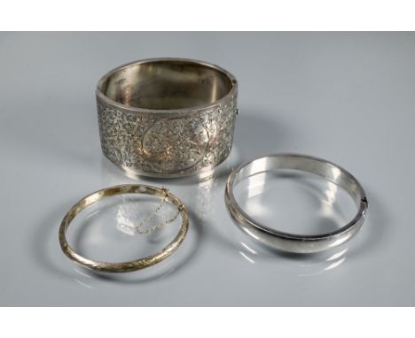 A wide white metal oval half-hinged bangle with engraved floral decoration to front, stamped 'sterl silver' to clasp, 3.8 cm 