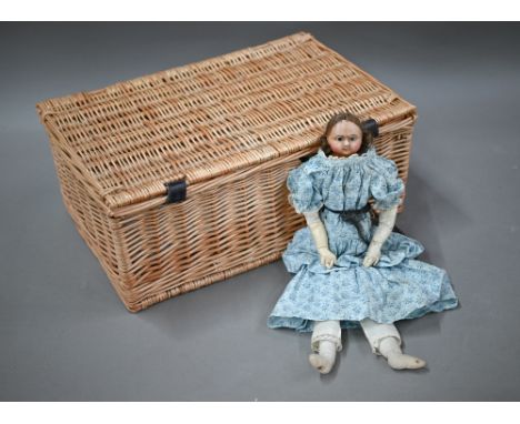 A 19th century wax-headed girl-doll with brown wig and fixed brown eyes, on stuffed fabric body with leather forearms, 35 cm 