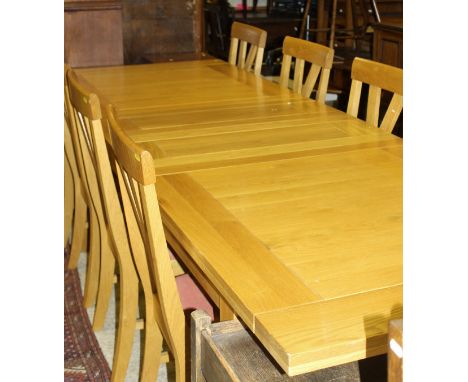 A modern light oak extending dining table, the plain top above square tapering legs, together with eight oak dining chairs wi