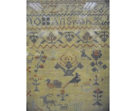 A 19th Century needlework sampler by Ann Smith featuring the alphabet, vase of flowers, numerals, etc, together with a 19th C