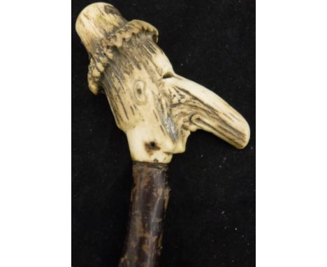 A 19th Century walking stick of small proportions, the handle a carved antler section as a leprechaun with a large nose and h