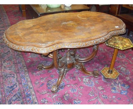 A Victorian walnut loo table in the Irish taste, the shaped top with carved edge raised on quadruped base with scroll and car