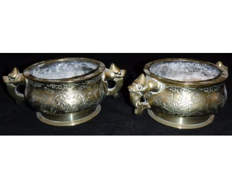 A pair of Chinese polished bronze censers with decoration of winged deer and bird and dragon and bird, raised on a circular f