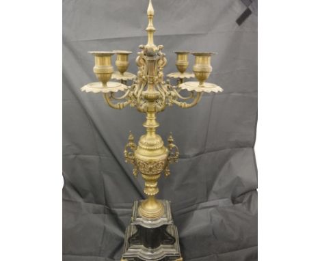 A pair of 19th Century brass four branch candelabra, the four branches uniting on a turned and carved brass body, raised on a