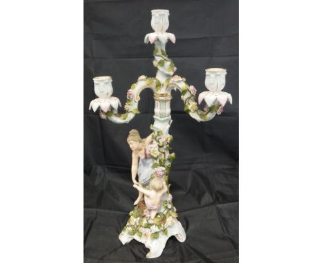 An early 20th Century German figural candelabra of a woman and child by a rose-encrusted pillar with three branch four light 