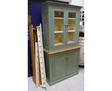 A modern painted pine kitchen cabinet with two glazed doors enclosing adjustable shelving over two cupboard doors on a plinth