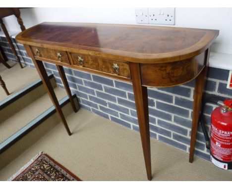 A walnut side table in the 19th Century manner, the shallow bow fronted top cross-banded over two frieze drawers on square ta