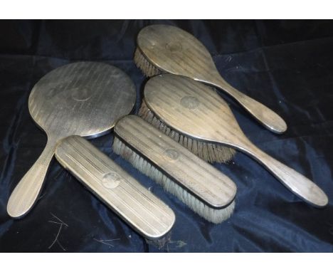 A matched five piece dressing table brush set with engine turned decoration
