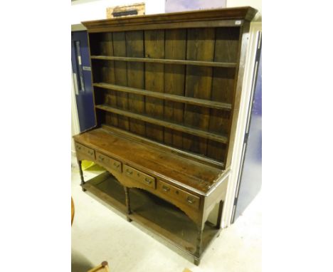 An 18th Century oak dresser with the three tier plate rack above a plain top, four short drawers each with brass swan neck ha