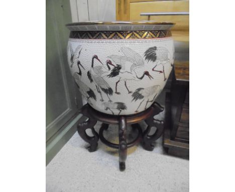 A 20th Century Chinese porcelain fish bowl decorated with storks, the interior with fish amongst lily pads, raised on a hardw