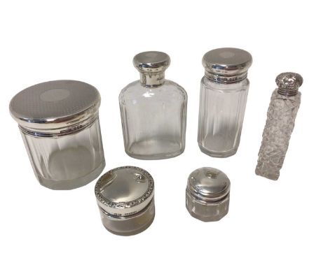 Group of six silver-topped glass bottles and jars, including a set of three George V with engine-turned decoration