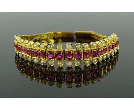 An unmarked gold ruby and pearl set articulated bracelet, set with 21 graduated rubies flanked by a row of split pearls, sett