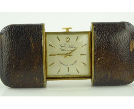 A gold plated Shields travelling clock in leather case, open outer case width 80mm, working order.