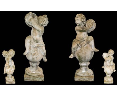 A Pair Of Well Weathered Reconstituted Stone Putti Figures Each depicted sat on sphere and socle plinths. The first holding a