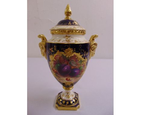 A Coalport vase and cover with gilded rams mask side handles the sides painted with fruits, the domed pull off cover with bud