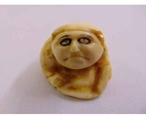 A Netsuke carved figure of an elder in caricature form
