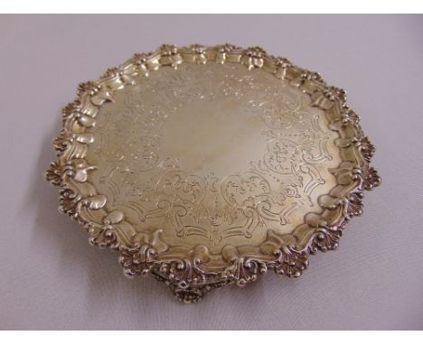 A Victorian silver salver circular engraved with scrolls and leaves, with shell border and bracket feet, London 1869