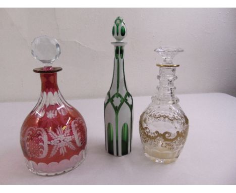A ruby etched glass decanter with glass drop stopper, a Georgian glass decanter with gilt decoration and drop stopper and a g