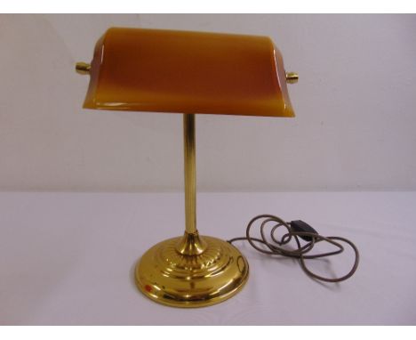 A brass desk lamp on raised circular base with integrated glass shade