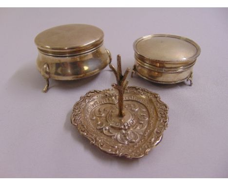 Two silver circular trinket boxes with hinged covers and a silver heart shaped ring stand