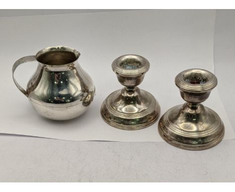A pair of silver candlestick holders hallmarked Birmingham 1978 together with a white metal milk jug stamped 900, weight of m