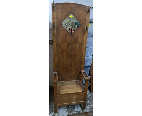 An early 20th century oak hall stand with cast iron coat hooks, diamond shaped mirror back, the seat with hinged top flanked 