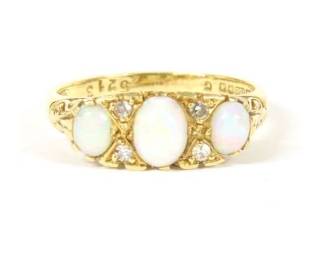 An 18ct gold three stone cabochon opal ring, with pairs of diamonds points all claw set to a scrolling heads and a plain poli