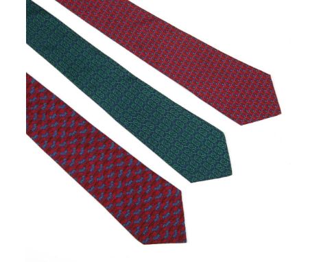 Three Hermès silk ties, to include a navy silk ground tie with a printed green horseshoe motif, a red silk ground tie with a 