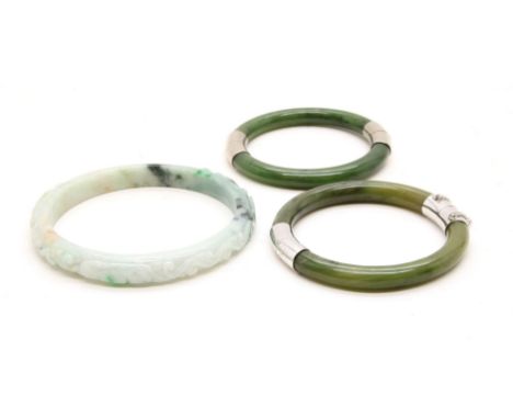 A Chinese jade bangle, carved with foliage, and two other plash bangles