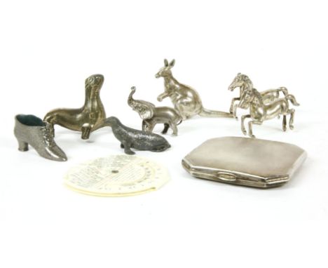 A silver engine turned compact, of square cut corner form, a silver elephant, a shoe form pin cushion, a five white metal ani
