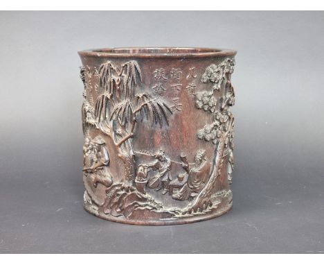 A Chinese carved hardwood brush pot, Qing, probably zitan, inscribed, relief carved and pierced with figures in a continuous 