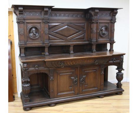 A late 19th century large carved oak breakfront sideboard, the back with central open shelf between two cupboards doors, each