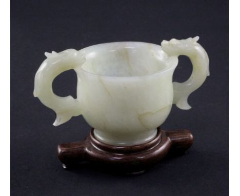 A Chinese bowenite jade two handled cup, Ming dynasty or later, of baluster form, applied with a pair of dragon scroll handle