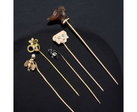 Five assorted early 20th century stick pins, including a French 18ct gold and chalcedony dog's head and a carved coral mask, 