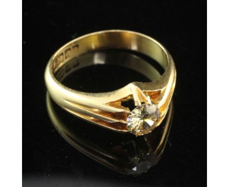 A George V 18ct gold and claw set solitaire diamond ring, with pierced shoulders, the round cut stone weighing approximately 