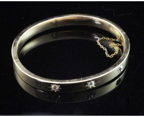 A gold and gypsy set three stone diamond hinged bangle, unmarked, gross weight 12 grams.