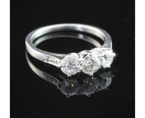 A platinum and three stone diamond ring, set with round brilliant cut stones and diamond set shoulders, size L.