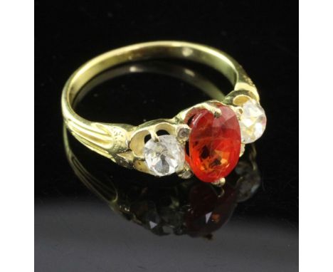 A gold and three stone orange sapphire and diamond ring, set with oval cut sapphire and flanked by old cut diamonds, size O.