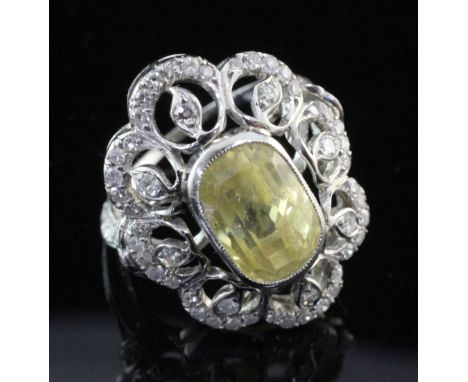 A white gold, yellow sapphire and diamond cluster dress ring, set with oval cut sapphire weighing in excess of 6.00ct, size M