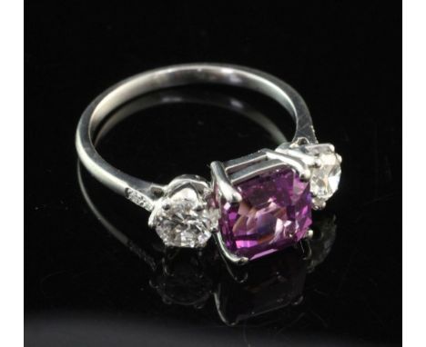 A white gold and three stone purple sapphire and diamond ring, set with square cut sapphire and flanked by round cut diamonds