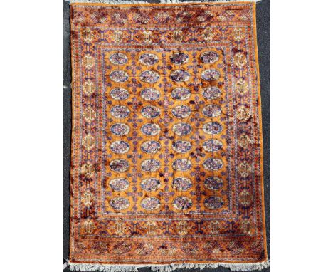 A Bokhara carpet, with field of thirty six polygons, on a burnt orange ground, with three row geometric border, 8ft 9in by 6f